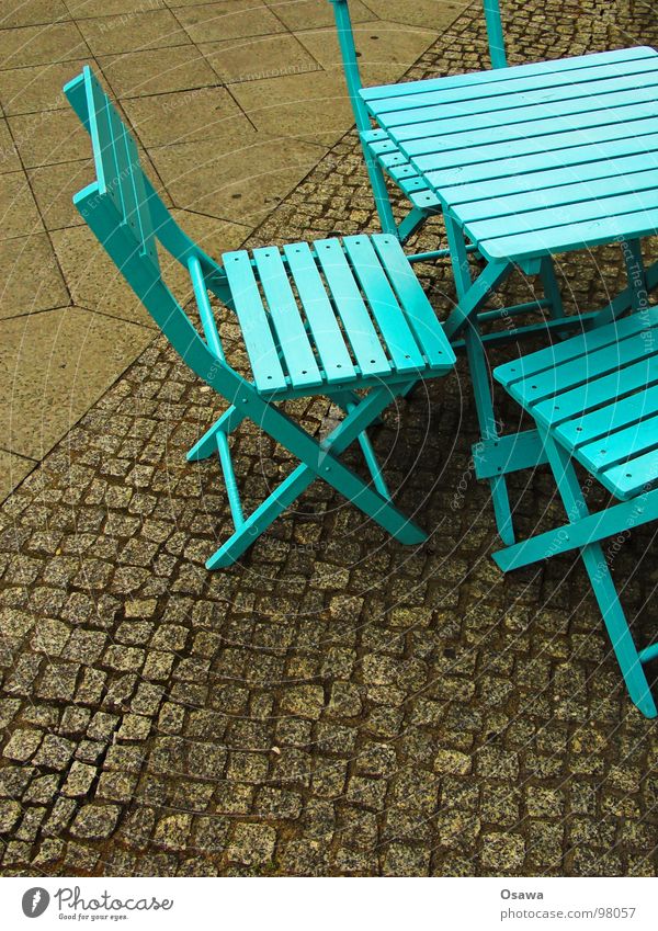 Straßenmöblierung in Cyan Möbel Tisch Stuhl Holz Café Straßencafé zyan grün grün-blau Bürgersteig Kopfsteinpflaster Verkehrswege Campingstuhl Pflastersteine
