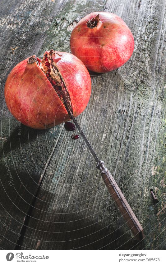 Granatapfel auf Holztisch Frucht Essen Vegetarische Ernährung Saft Tisch Natur frisch saftig rot Farbe hölzern Messer reif Hintergrund organisch Gesundheit süß