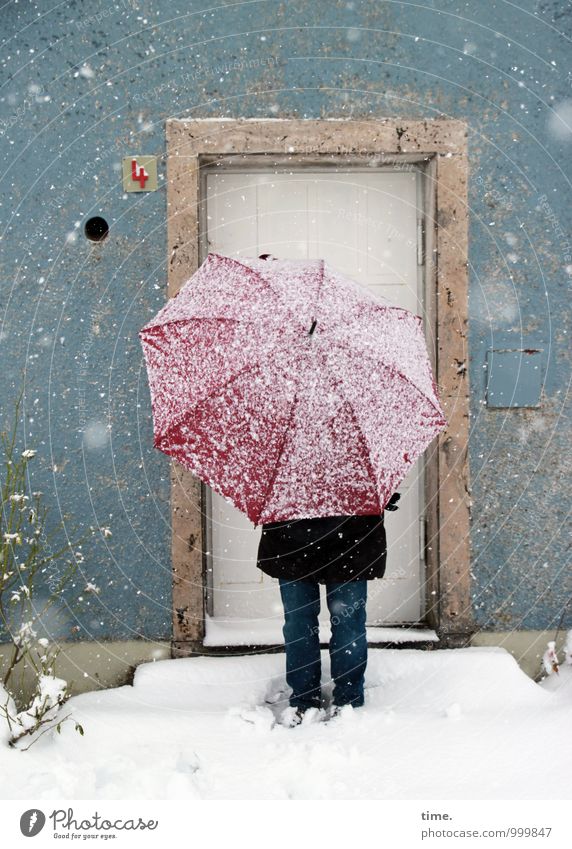 Rotschirmchen II 1 Mensch Winter Schnee Schneefall Haus Mauer Wand Fassade Tür Hausnummer Jeanshose Mantel Regenschirm festhalten stehen kalt selbstbewußt
